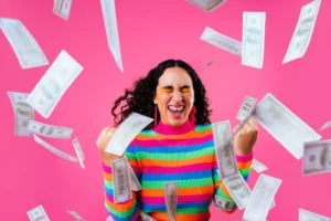 Joyful woman with falling money on pink background