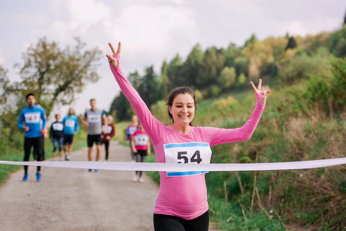Joyful female runner winning race showing peace sign