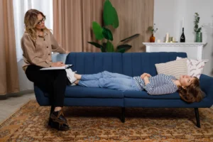 A therapist takes notes while a client relaxes on a couch during a counseling session. How can financial therapy help women in 2025