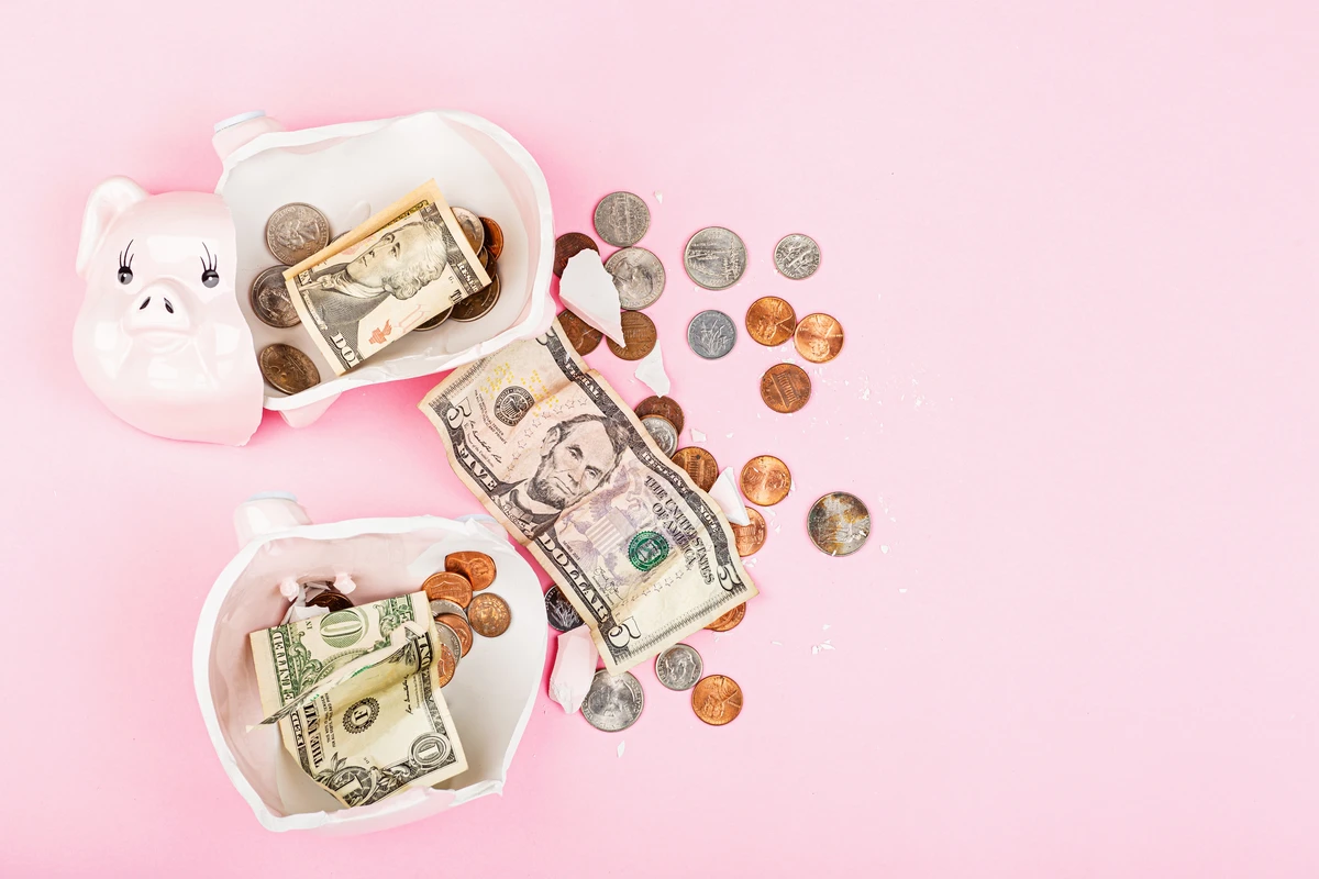 Piggy banks spilling coins and cash on a pink background, illustrating savings and financial management.