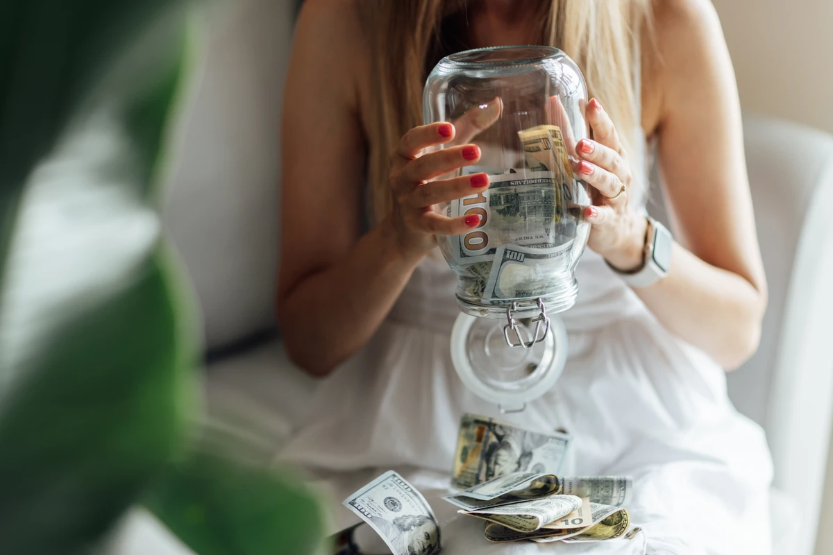 a woman holding a jar full of money