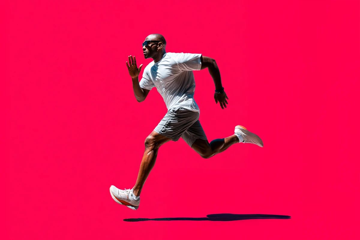 A man in athletic wear runs energetically against a bright pink background.