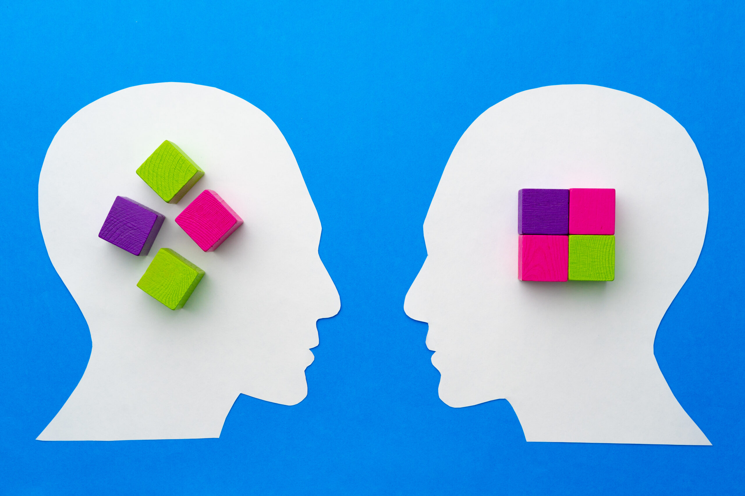 Colorful blocks arranged on paper profiles against a blue background, symbolizing creativity and thought.