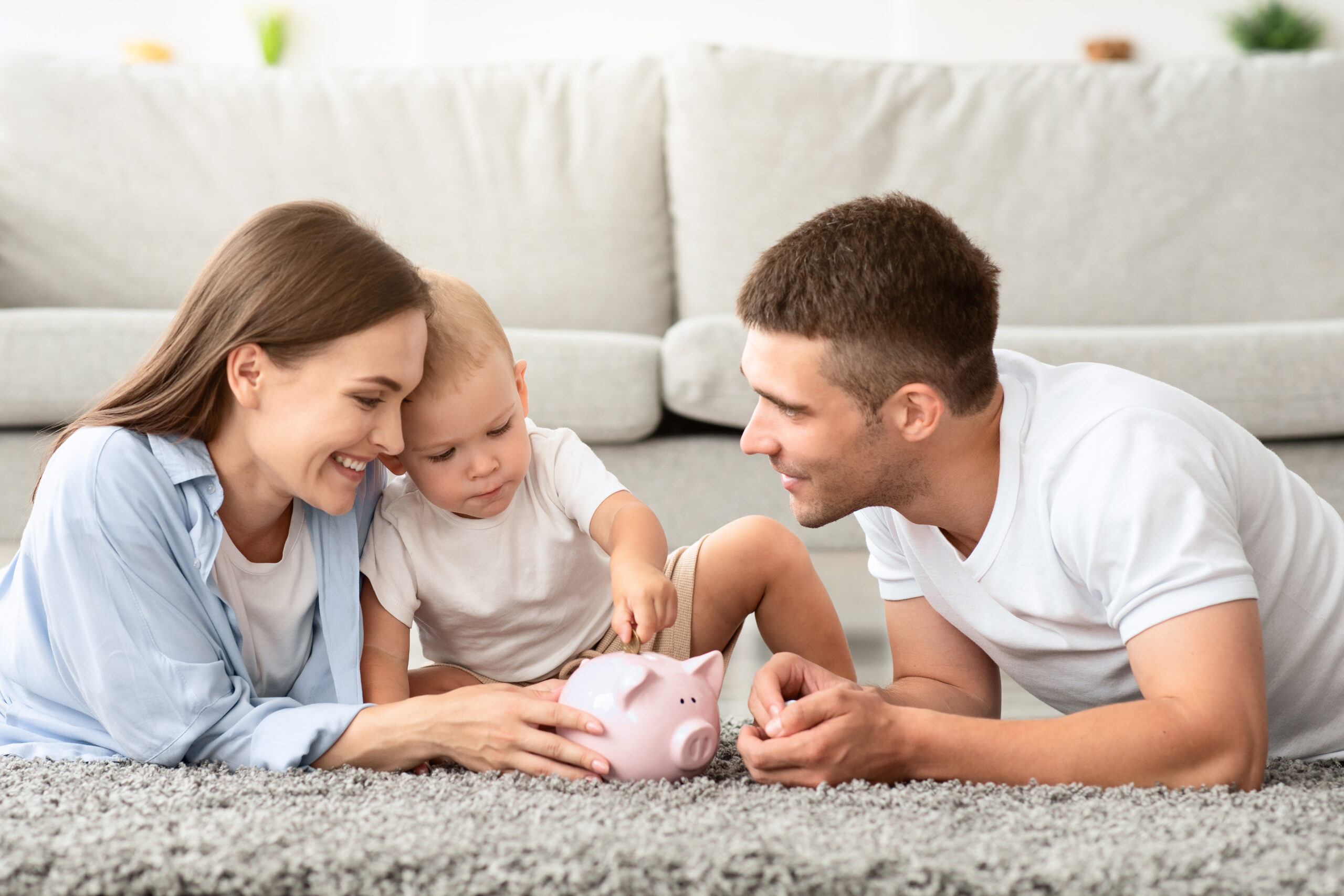 A family enjoys quality time together while teaching their toddler about saving money with a piggy bank. Smart ways to finance parenthood