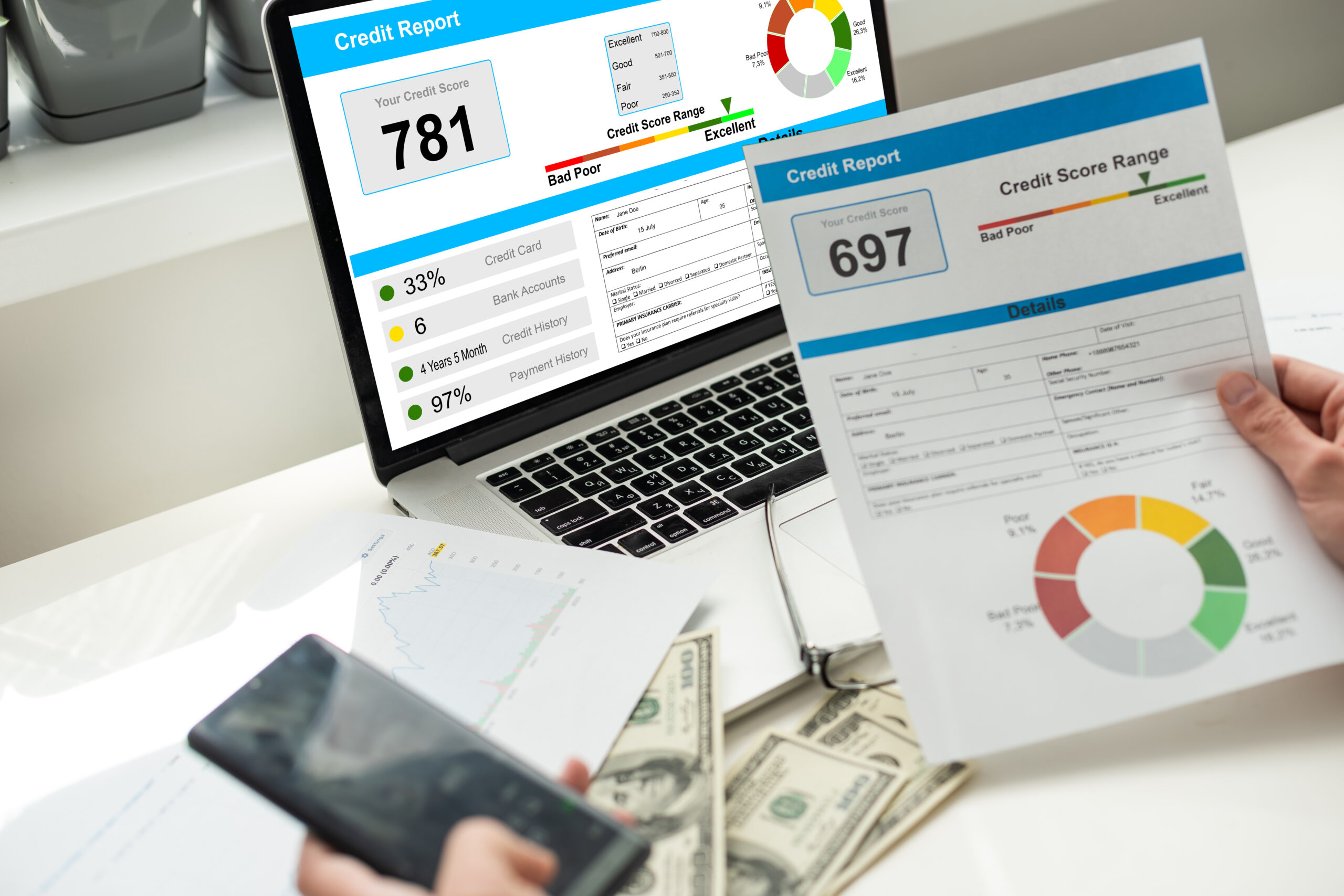 A person reviews credit reports on a laptop while holding a printed report and a smartphone, with cash on the table.