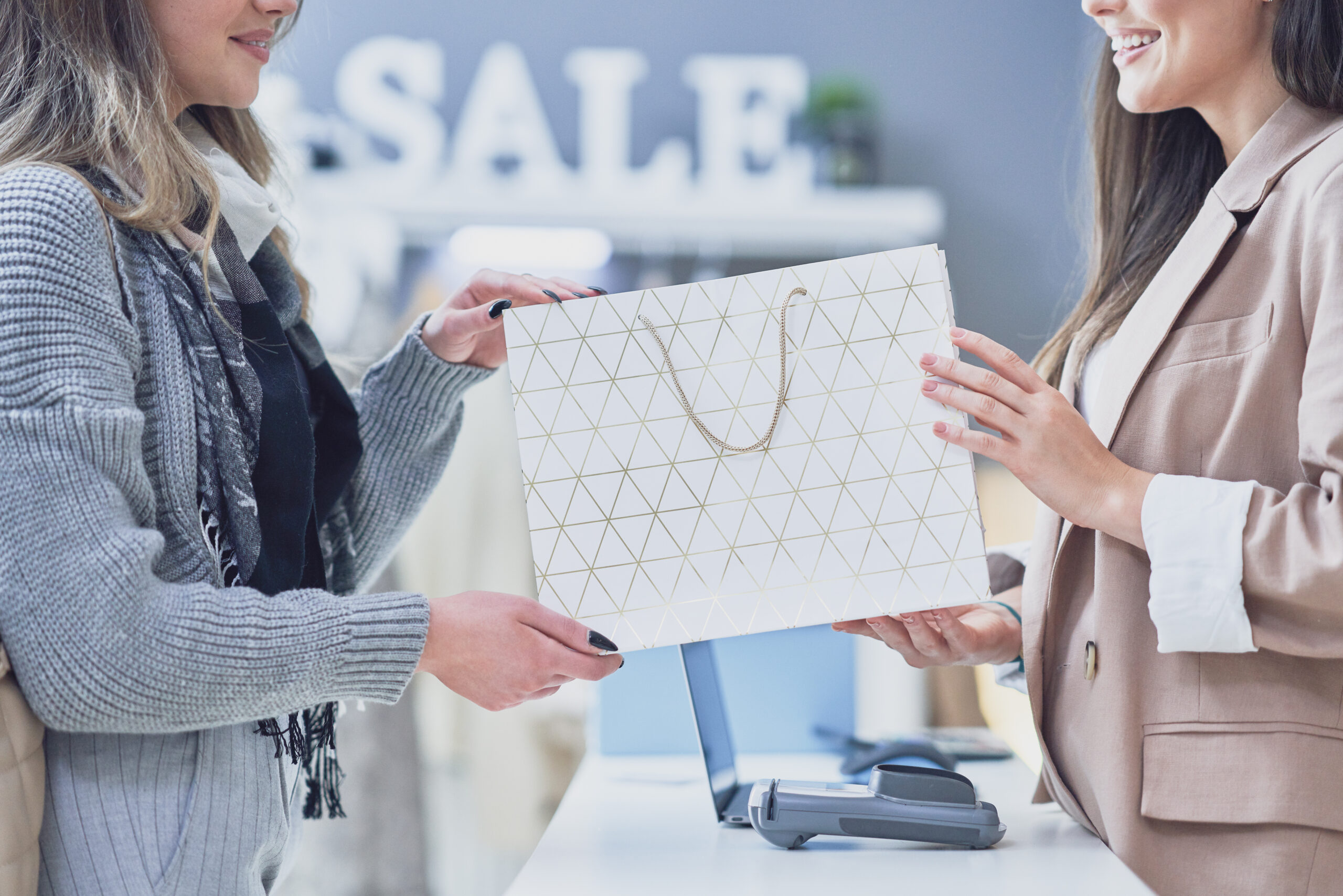 A customer receives a gift bag from a smiling sales associate at a retail store.