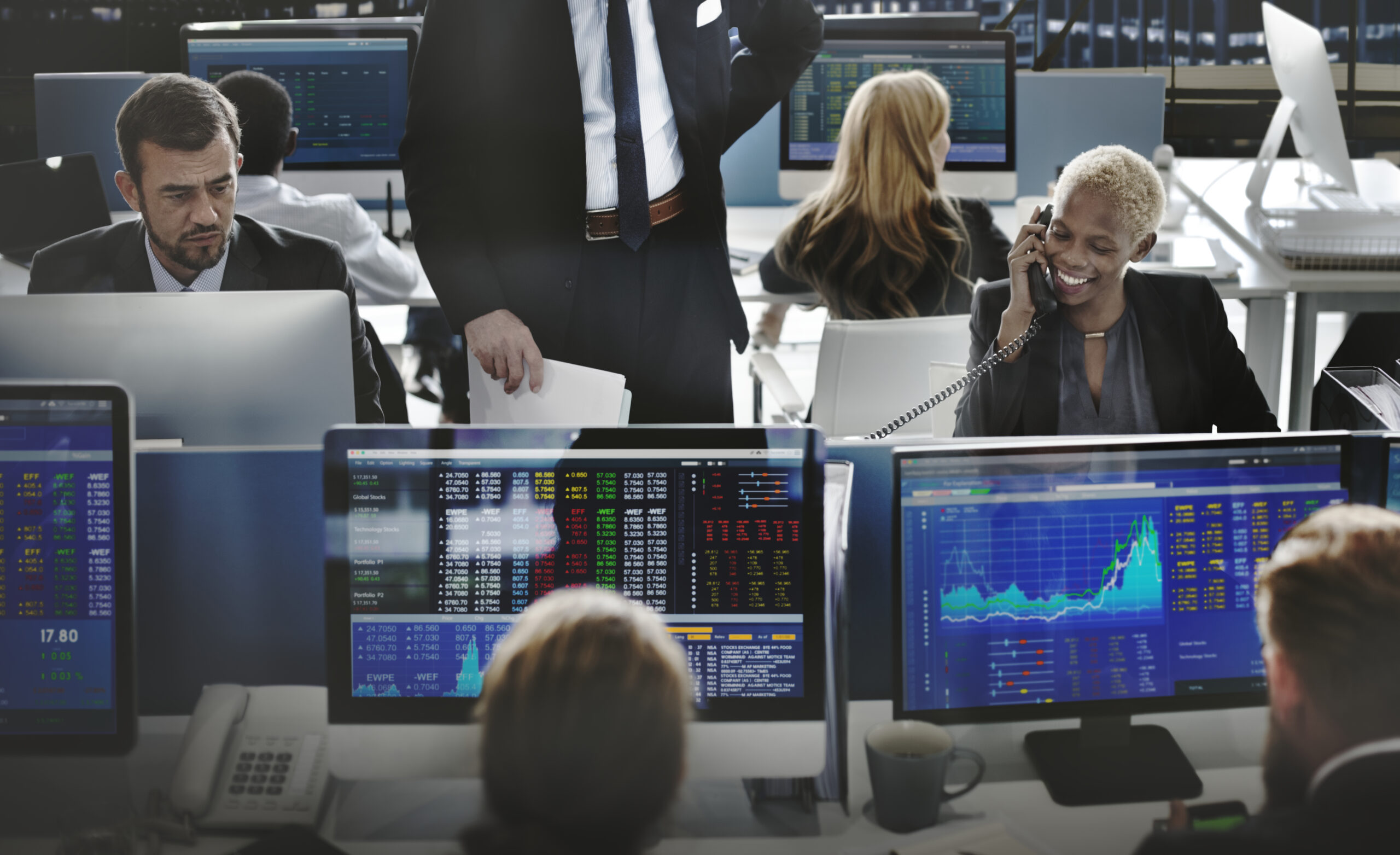 Business professionals analyze stock market data on multiple screens in a busy trading office. stock market myths debunked